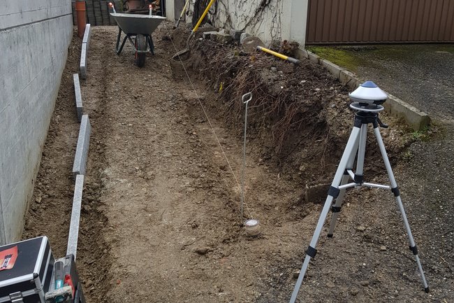 Travaux en cours de pose de bordures et muret