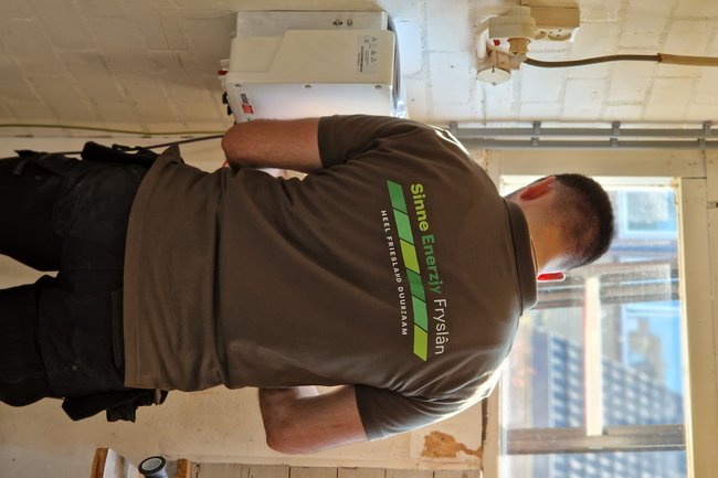 Hoofdmonteur bezig met het ophangen van de omvormer in de ga