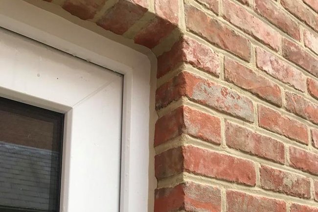 Tussen raam en muur afgekit.