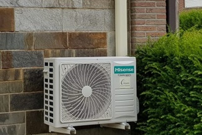 Hisense buitenunit, netjes verstopt achter een struik