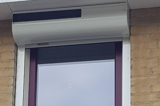 Rolluik op zonne energie onder de dakgoot en afgeronde kast