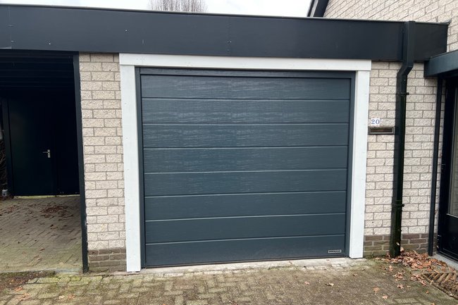 Deur met omtimmering ivm restanten oude houten poort.