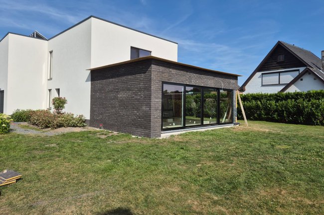 Bijbouw met grote ramen en modern metselwerk in opbouw.