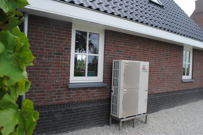 Warmtepomp voor woonhuis gemonteerd naast schuur.