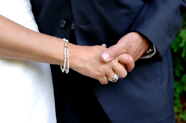 Huwelijkskoppel die elkaars hand vasthouden.